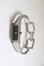 Load image into Gallery viewer, Gucci watch with a silver frame and black face on a white background